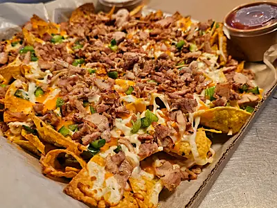A tray of loaded nachos with salsa and sour cream