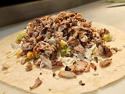 A chicken wrap laid open on the counter before it is rolled